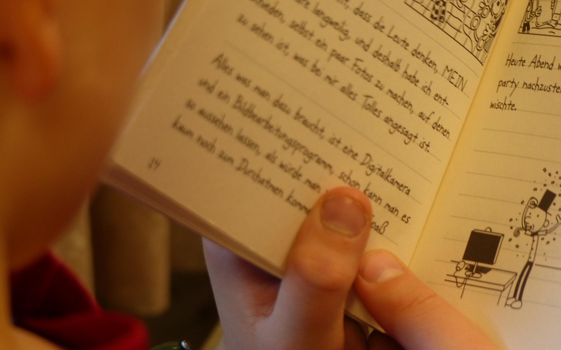Kind von der Seite mit aufgeschlagenem Buch