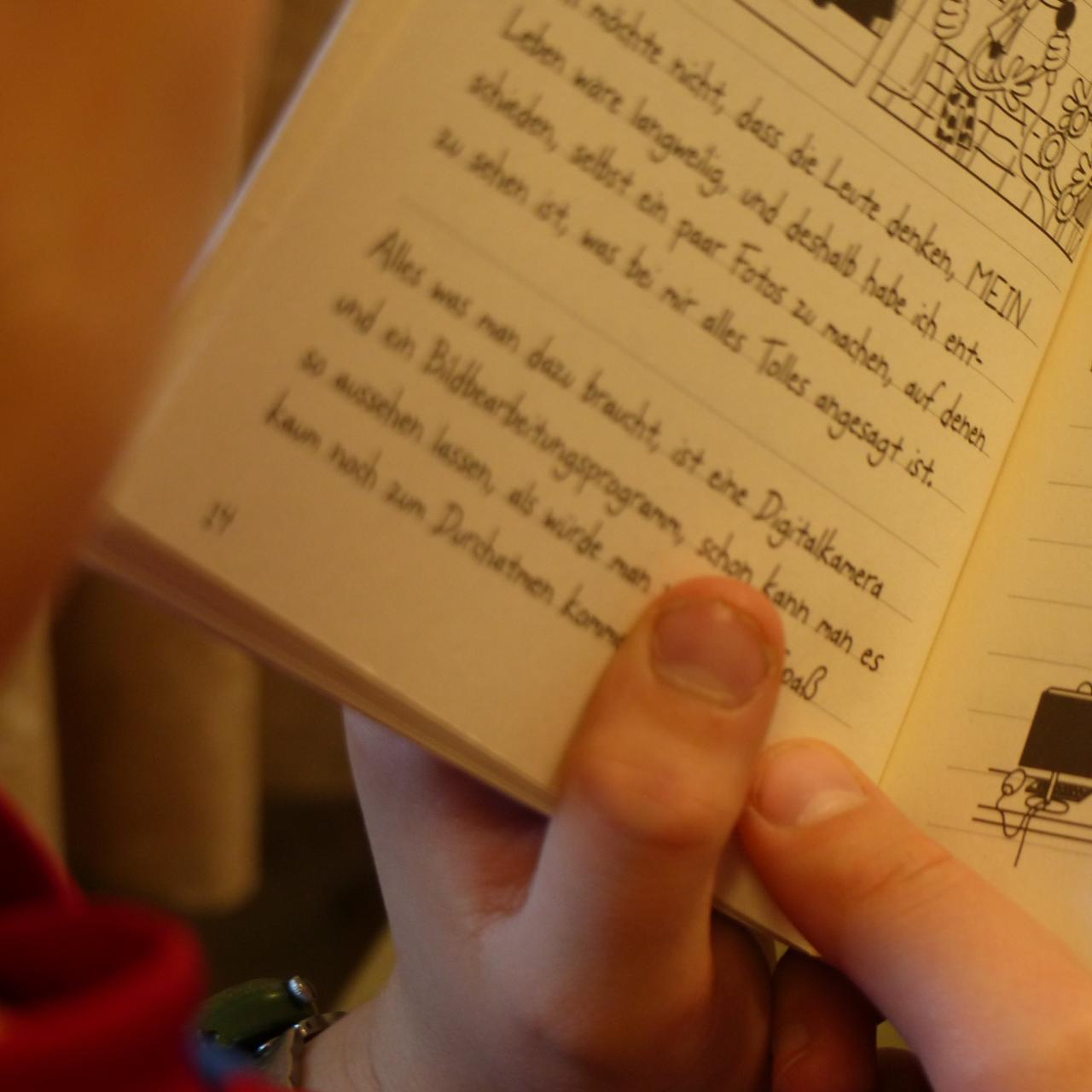 Kind von der Seite mit aufgeschlagenem Buch